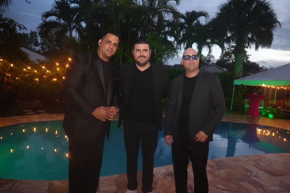 Three Consecuencia musicians standing beside a pool